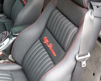 Primo piano dello schienale in pelle nera con impuntura rossa e logo Alfa Romeo ricamato in rosso