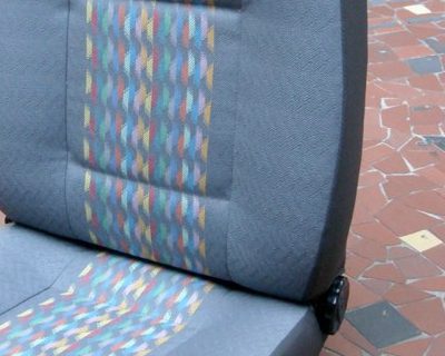 Primo piano del tessuto originale a fasce arancio, avorio e verde oliva di un sedile Iveco