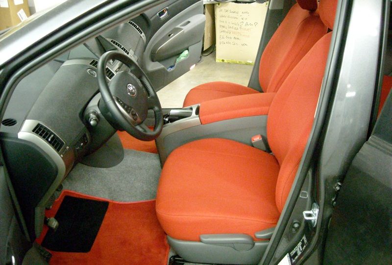 Abitacolo di una Toyota Prius con fodere su misura e tappeti in tessuto rosso