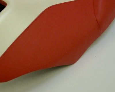 Primo piano della cucitura fra la finta pelle rossa e quella avorio di una sella rifoderata